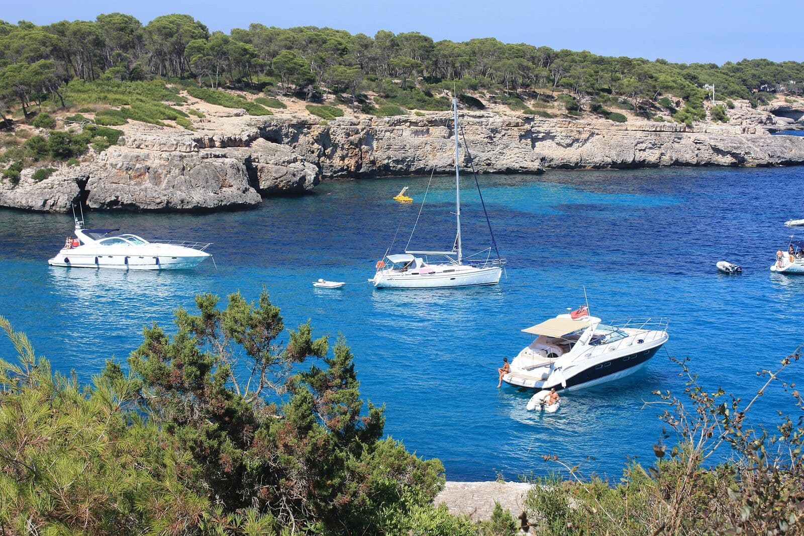 Cala Mondragó, no Parque Natural de Mondragó, com água turquesa, barcos ancorados e uma costa coberta de pinheiros