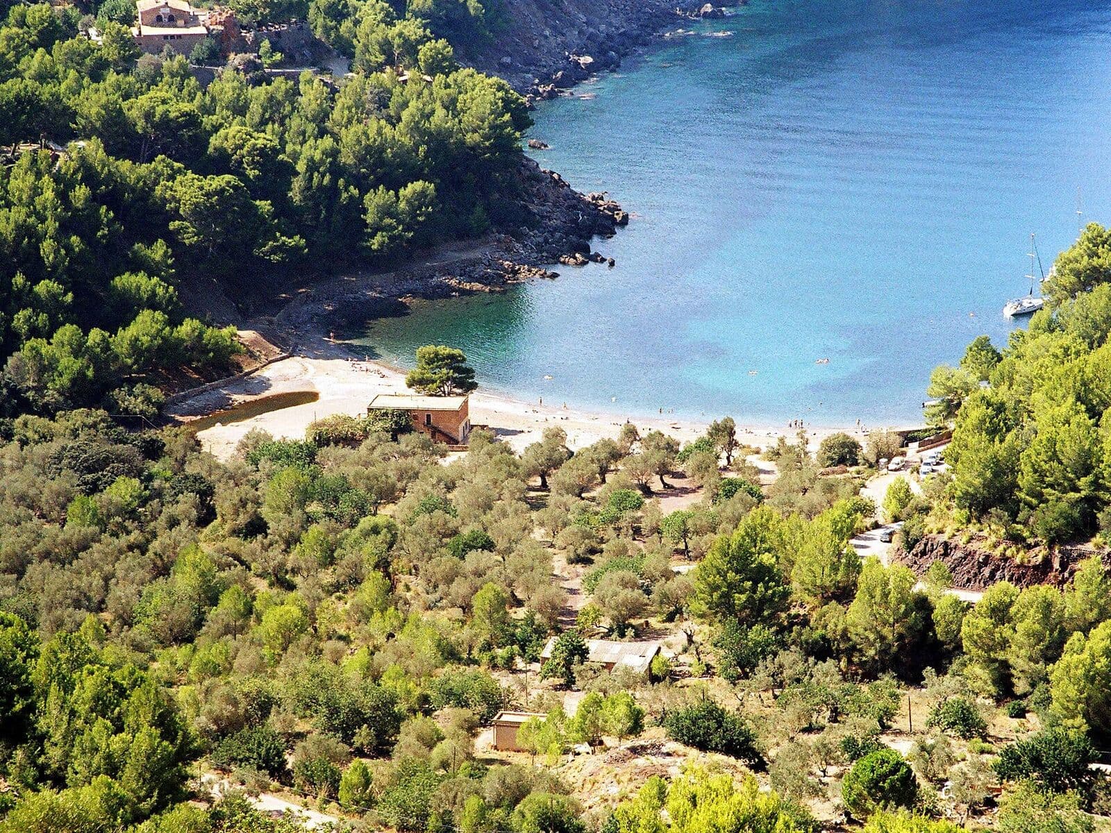 Cala Tuent vista do alto, com água azul e encostas cobertas de pinheiros