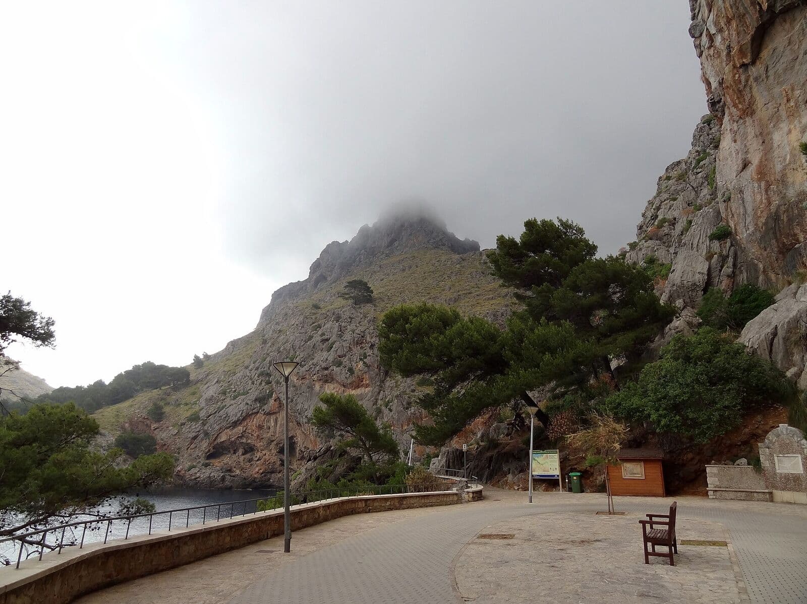 O caminho para pedestres de Sa Calobra entre paredes de rocha e pinheiros, num dia nublado
