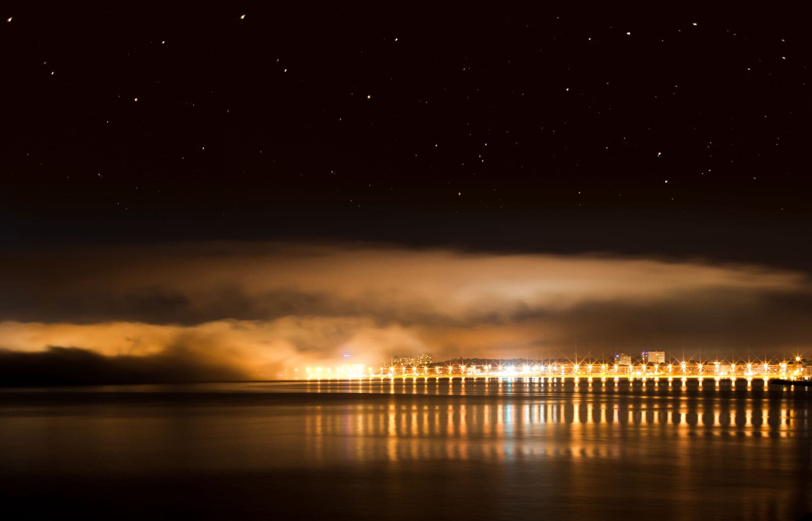Le luci della baia di Palma di notte, con un banco di nebbia sull'acqua