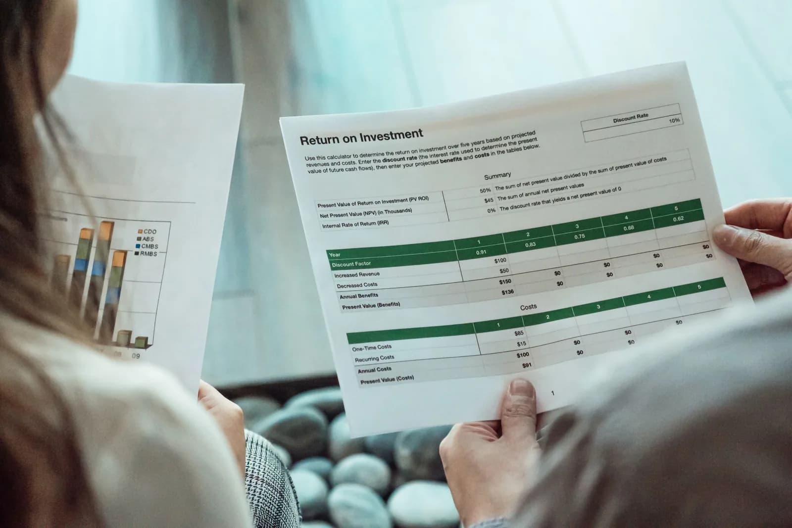 Two people review printed pages with charts and financial tables.