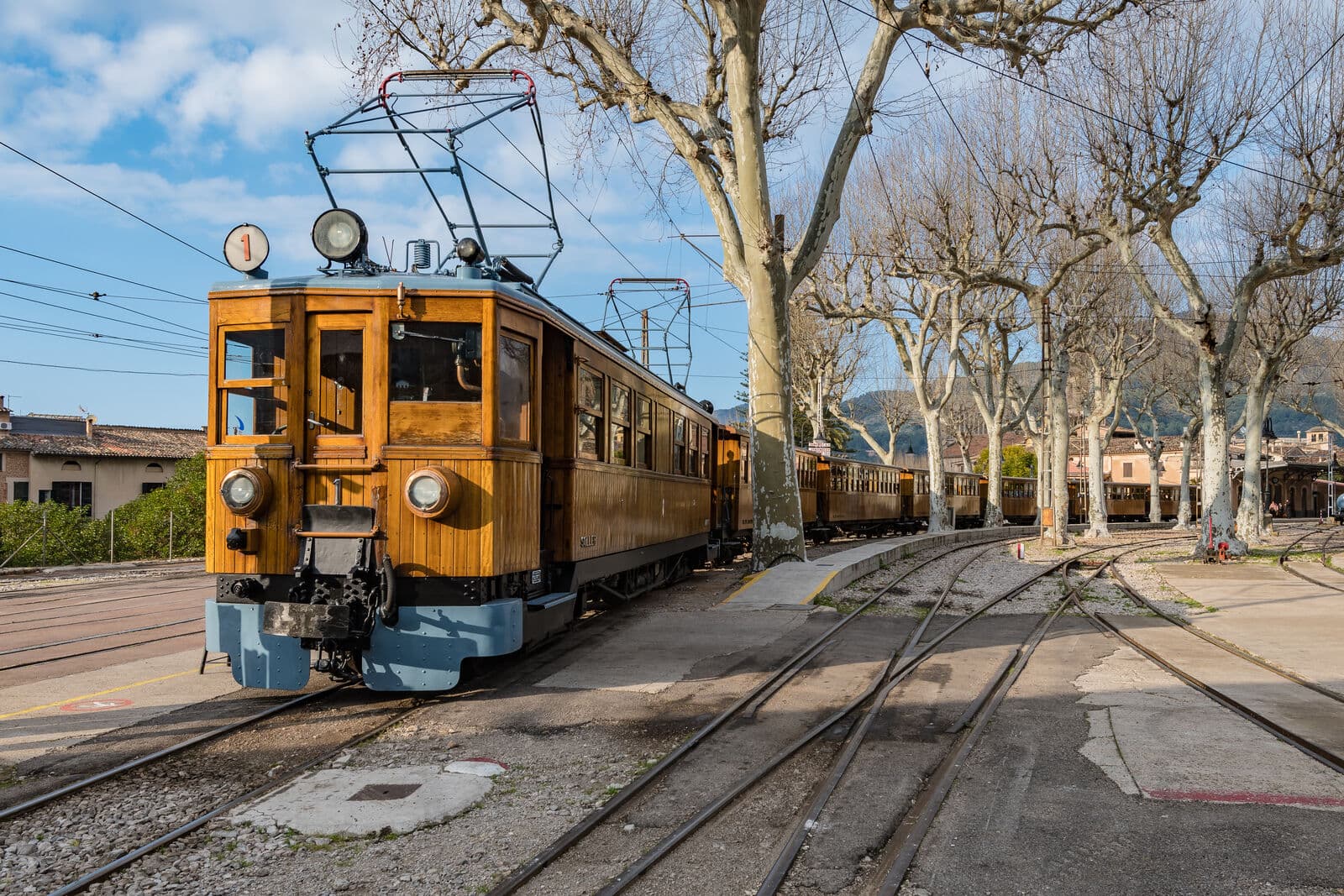 Automotriz de madeira do Trem de Sóller nos trilhos da estação de Sóller, entre plátanos sem folhas