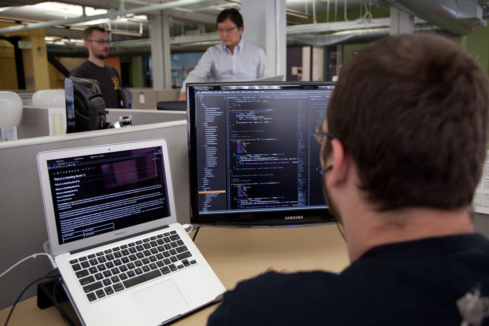 A programmer works at a laptop and monitor displaying code at the Wikimedia Foundation offices in San Francisco.