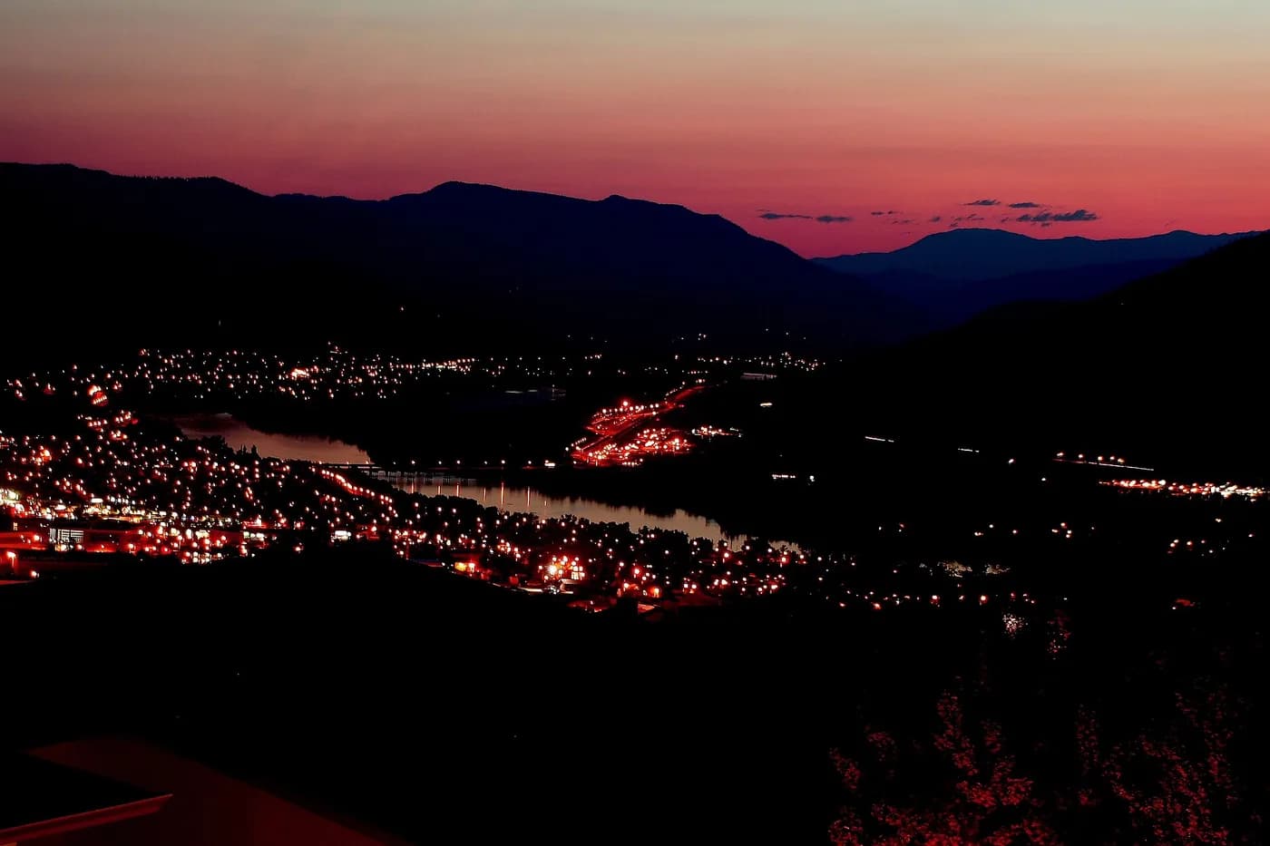 Cielo del amanecer sobre un pueblo y unas colinas, fotografiado desde una habitación; ilustra el cambio de luz natural, no una hora obligatoria para levantarse.