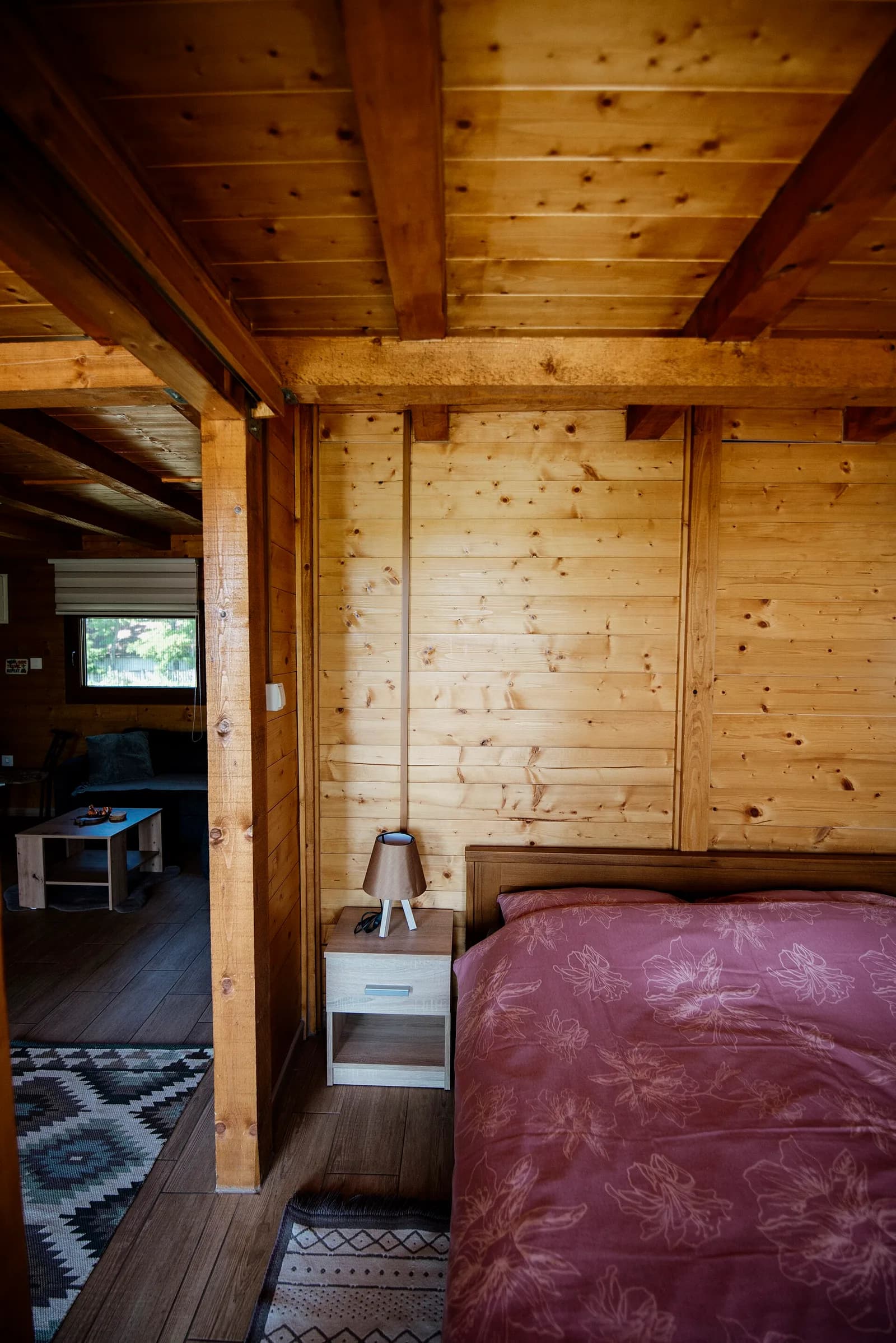 Dormitorio sencillo de madera con una cama, luz natural suave y tonos neutros tranquilos.