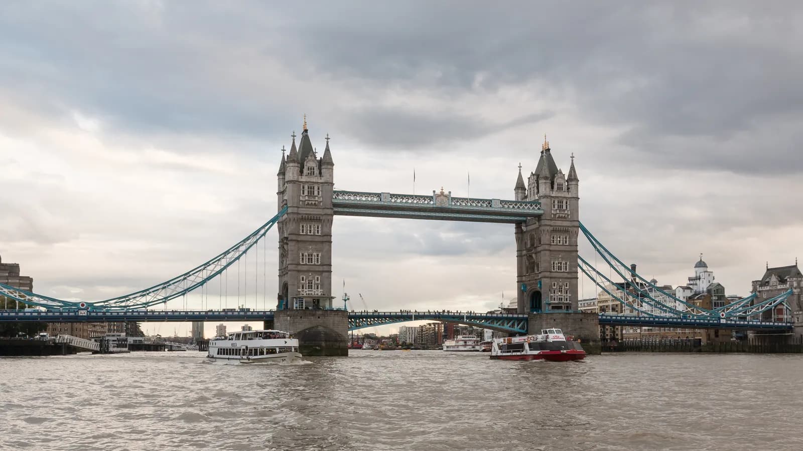 The two towers of Tower Bridge and its upper walkway over the Thames on a cloudy day.
