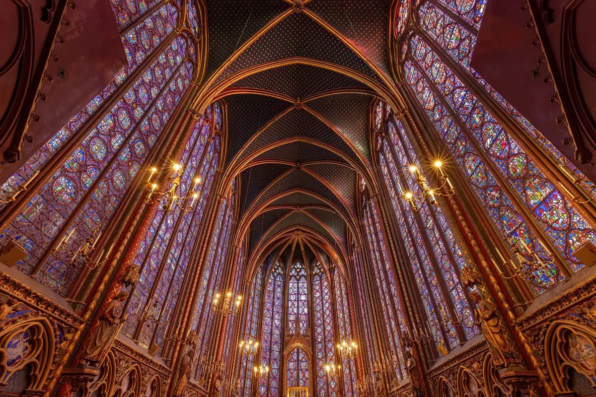 Upper chapel of the Sainte-Chapelle in Paris, with its coloured stained-glass windows and blue star-studded vault.
