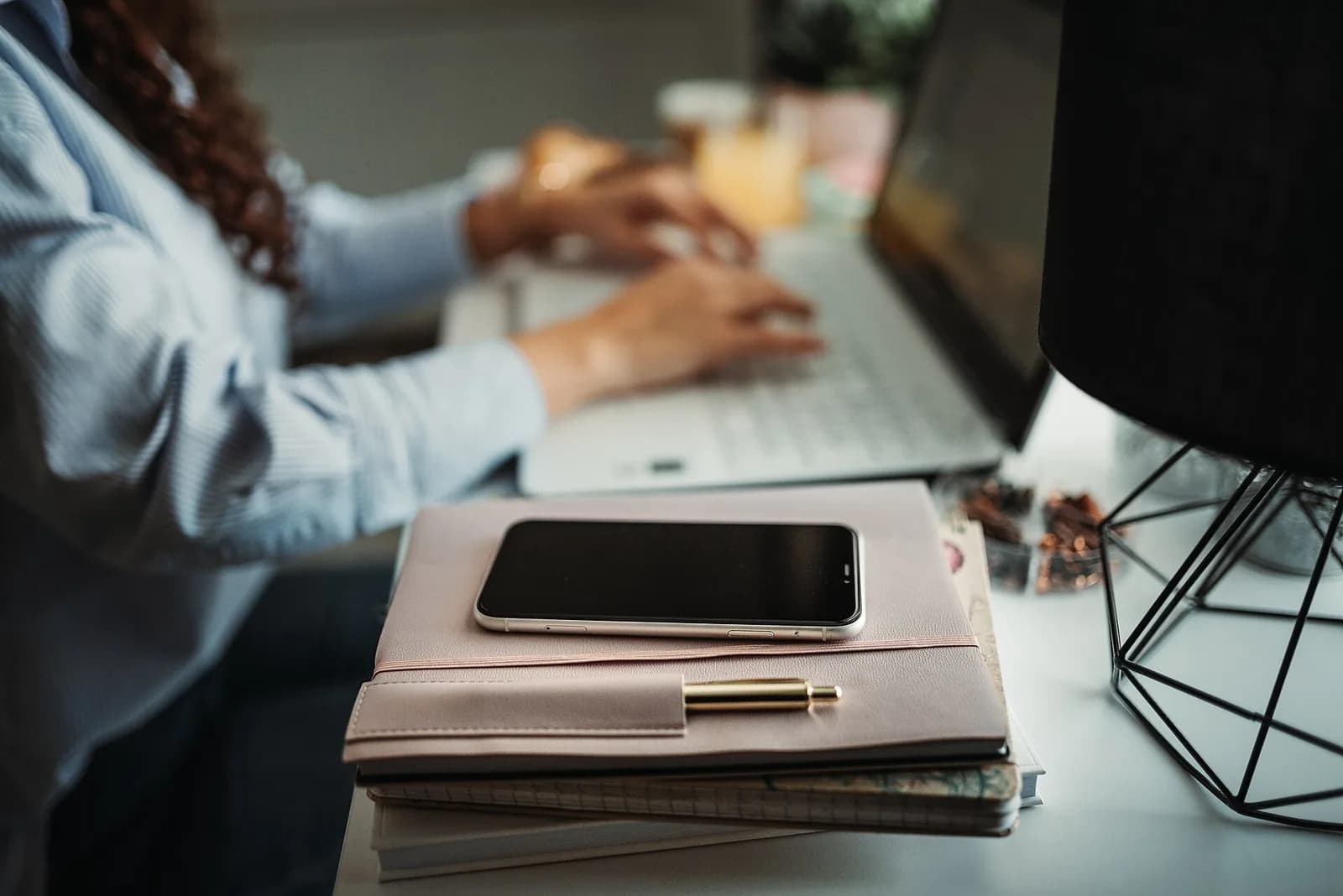 Una persona lavora al computer accanto a uno smartphone, un quaderno e un’agenda su una scrivania.