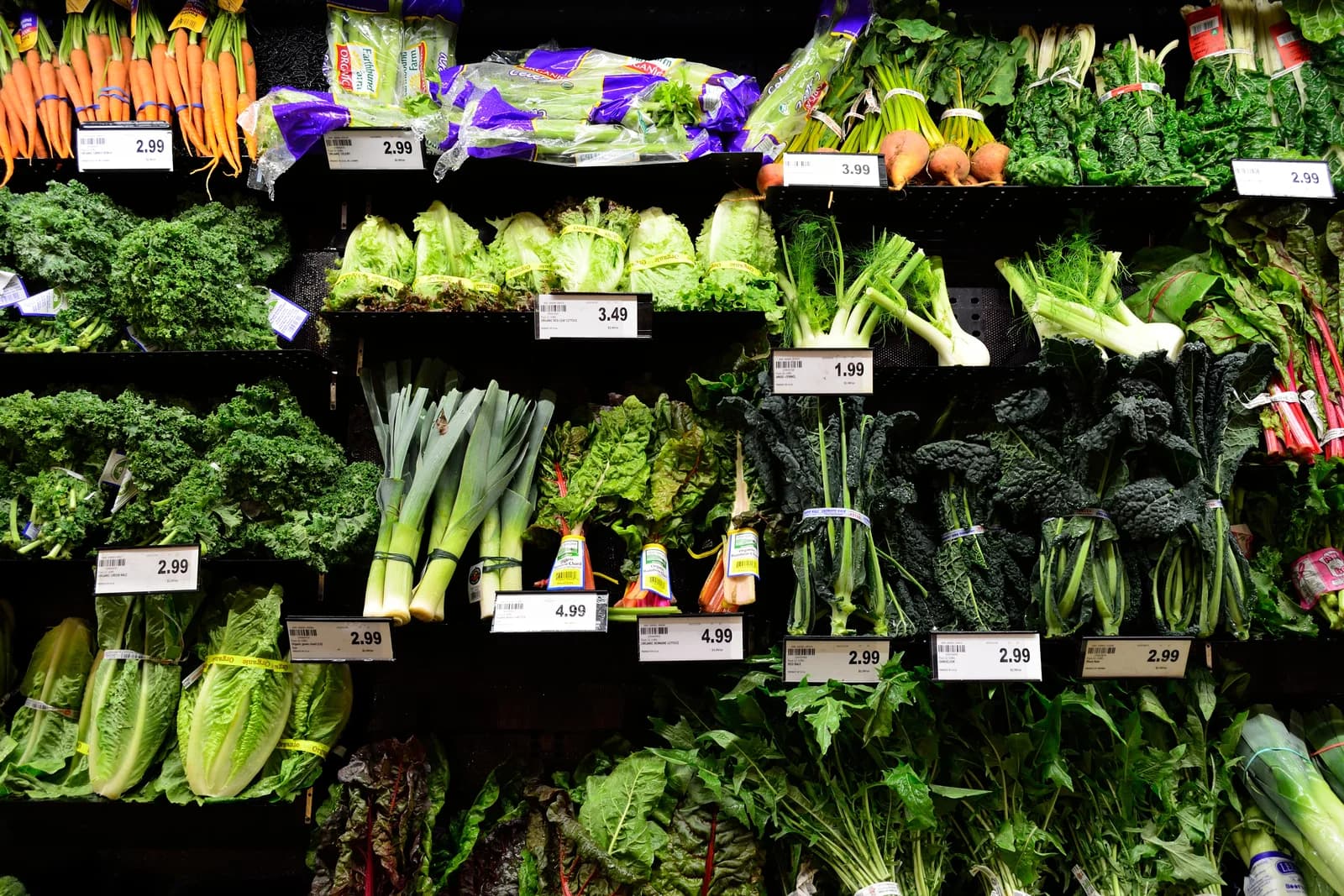Frisches Gemüse in einem Supermarkt mit Preisschildern.