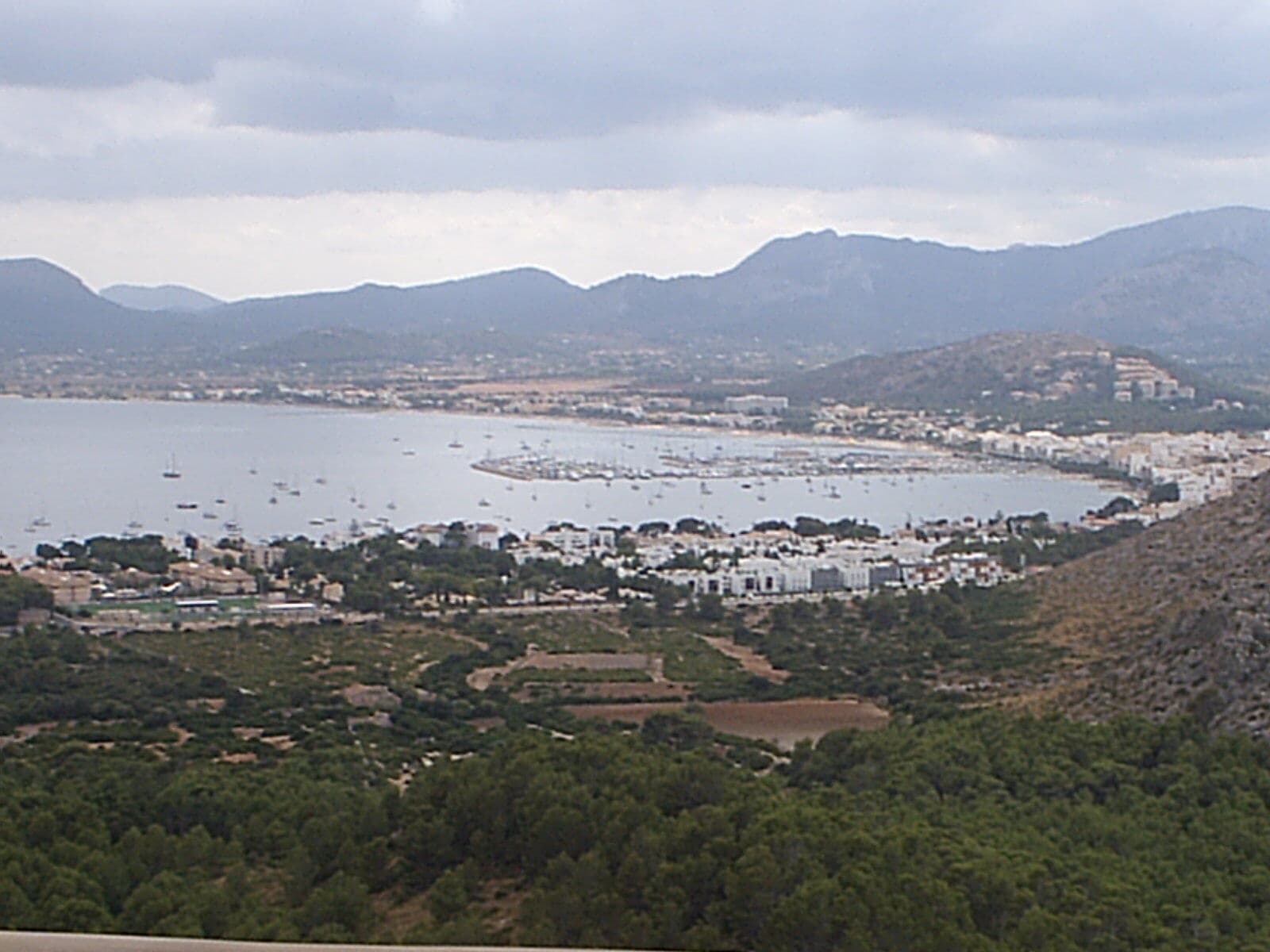 Vista da baía de Pollença a partir da montanha, com Port de Pollença, barcos ancorados e serras ao fundo