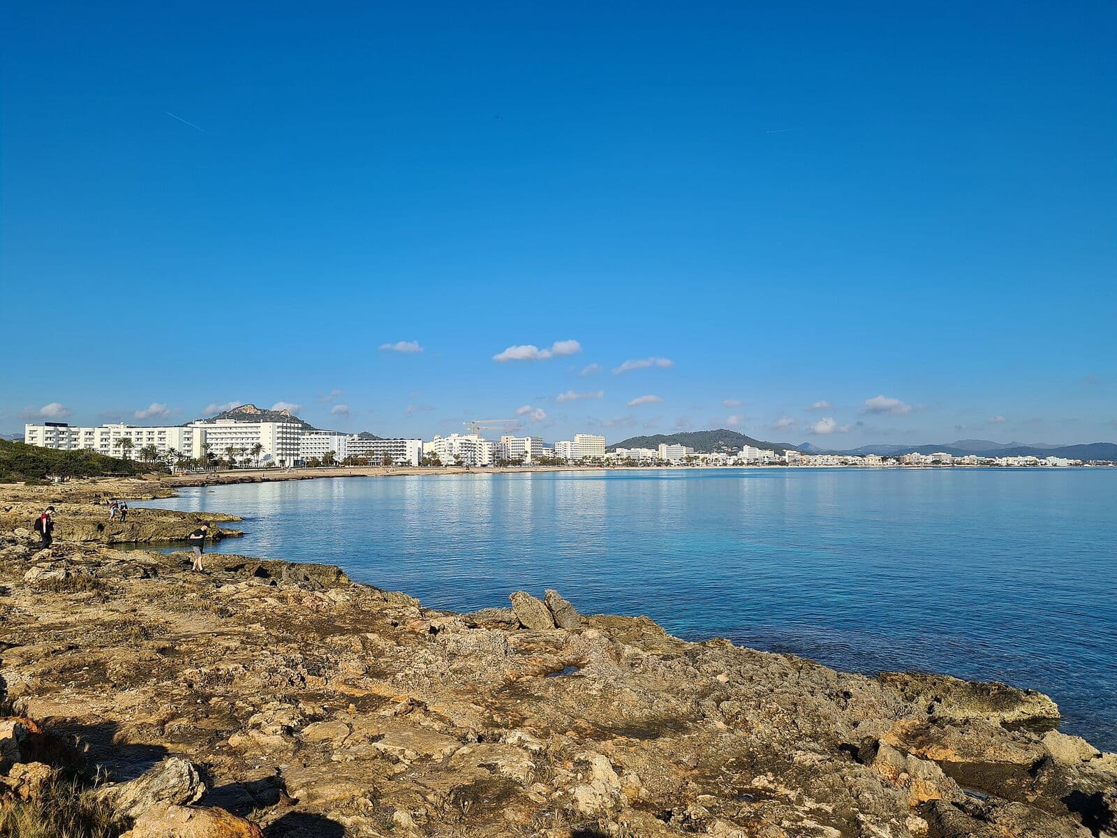 A baía de Cala Millor vista da costa rochosa, com a praia e uma fileira de hotéis ao fundo
