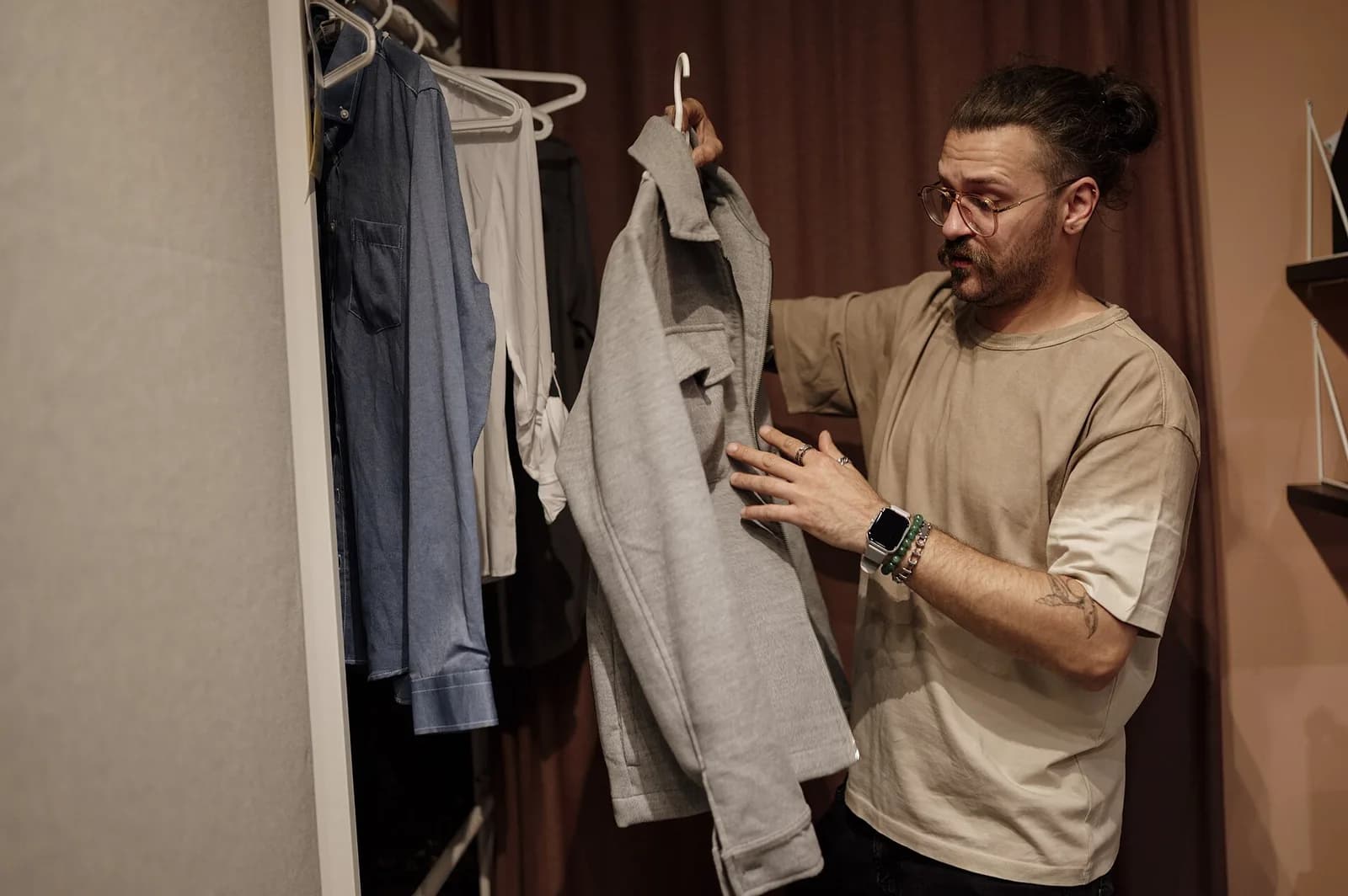 Une personne regarde des vêtements dans une penderie ; la photo montre un choix de vêtements, pas leur qualité ni leur durabilité.