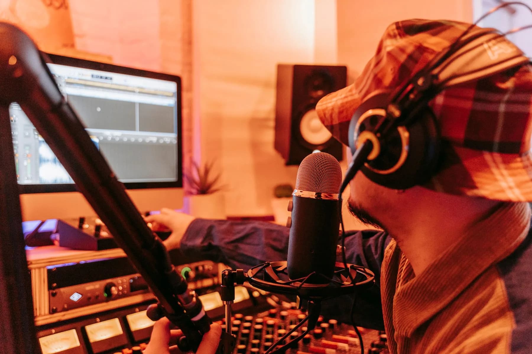 Una persona con cuffie parla davanti a un microfono da studio in una generica sessione di registrazione audio.