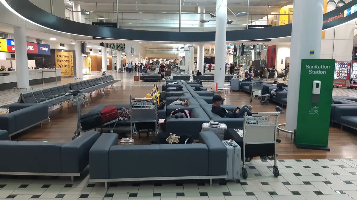 Pasajeros durmiendo en los sofás de la terminal internacional del aeropuerto de Brisbane, de noche.