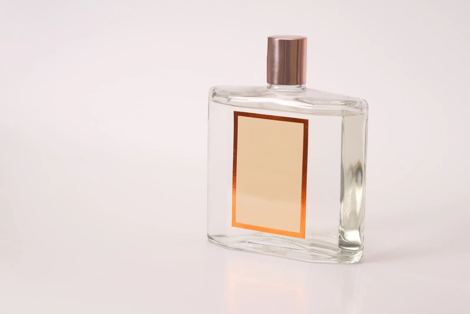 Flacone di profumo trasparente e senza marchio fotografato su uno sfondo chiaro.