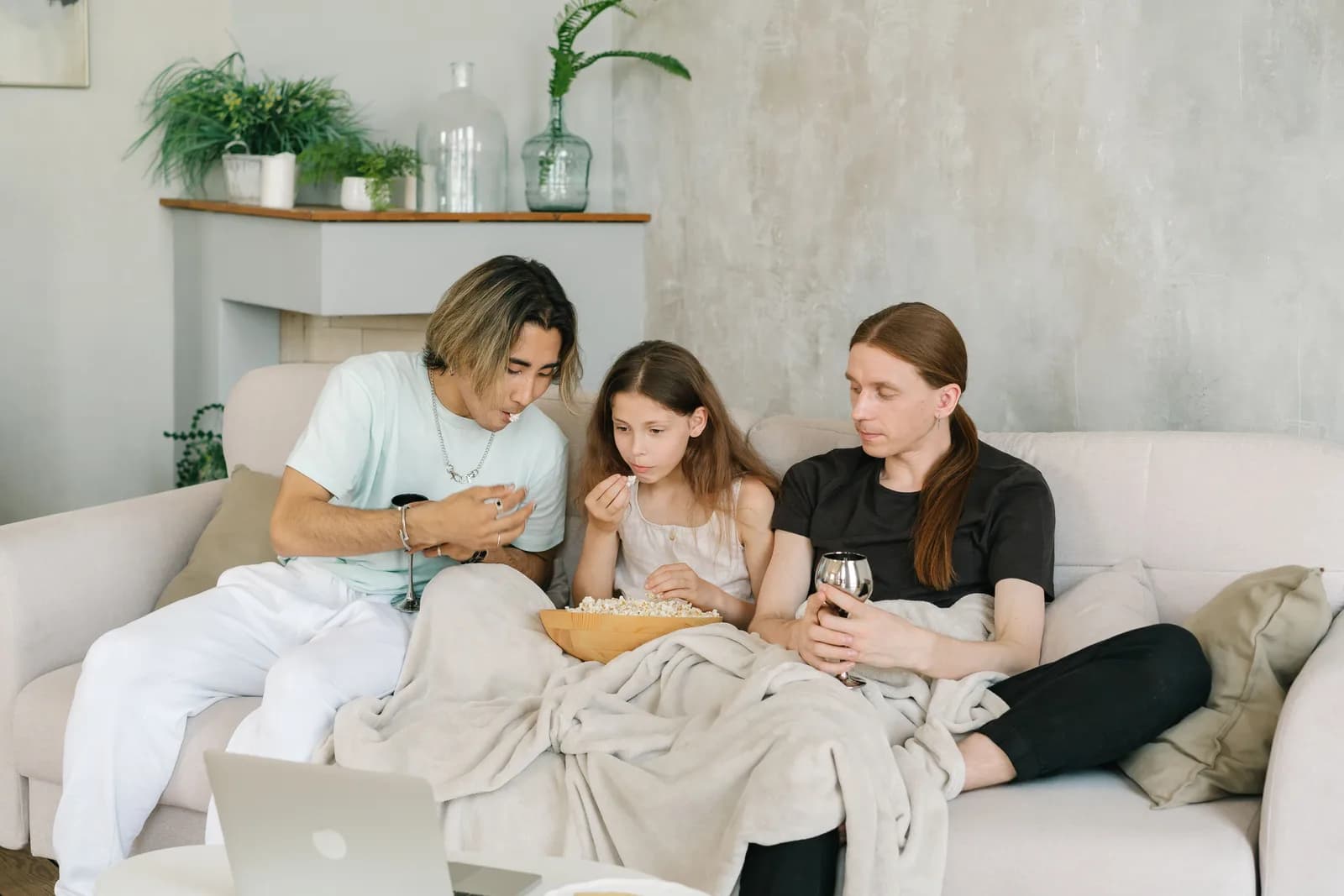 Family watching a movie on a laptop at home with popcorn.