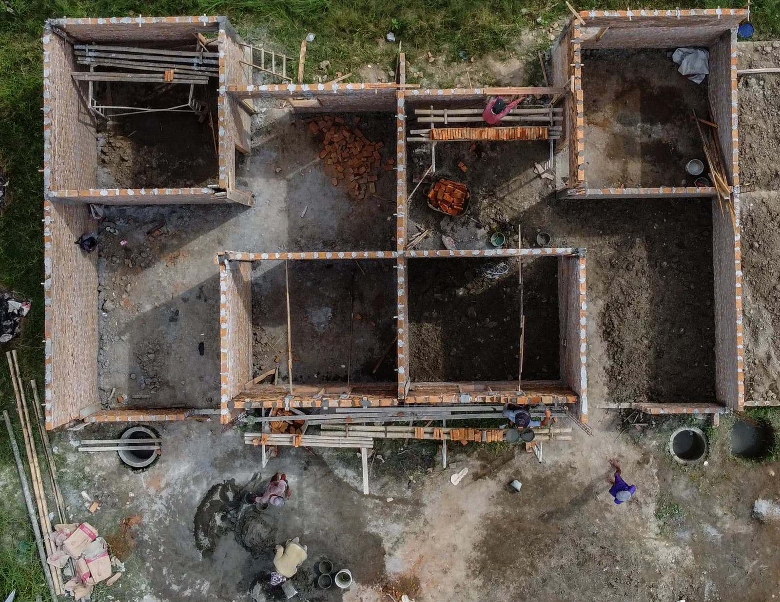 Luftaufnahme eines im Bau befindlichen Ziegelhauses, dessen Mauerwerk mehrere Räume abgrenzt.