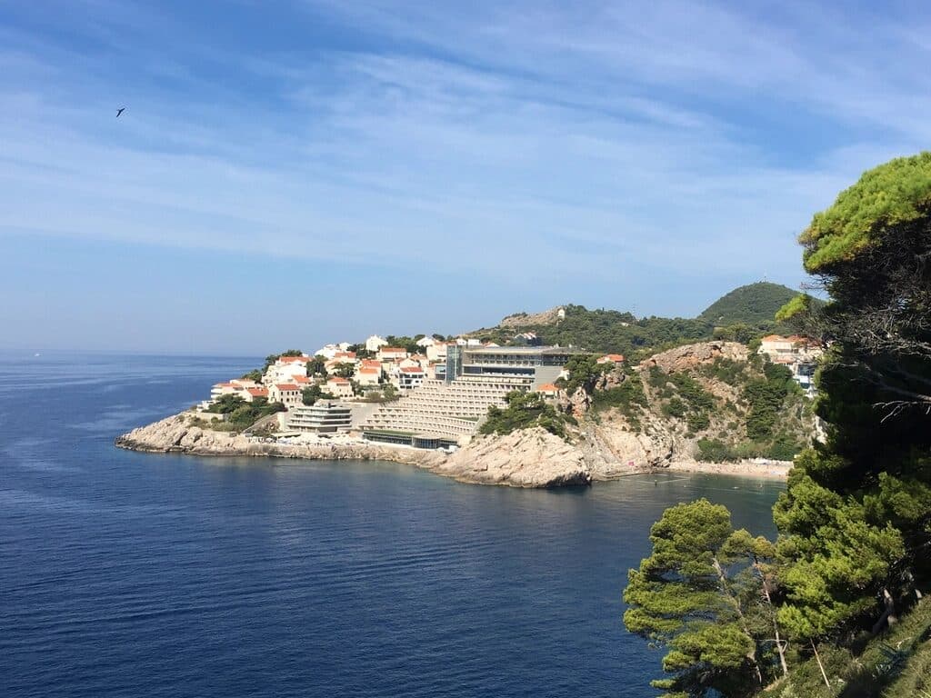 Pine-covered headland above a calm, deep blue Mediterranean sea